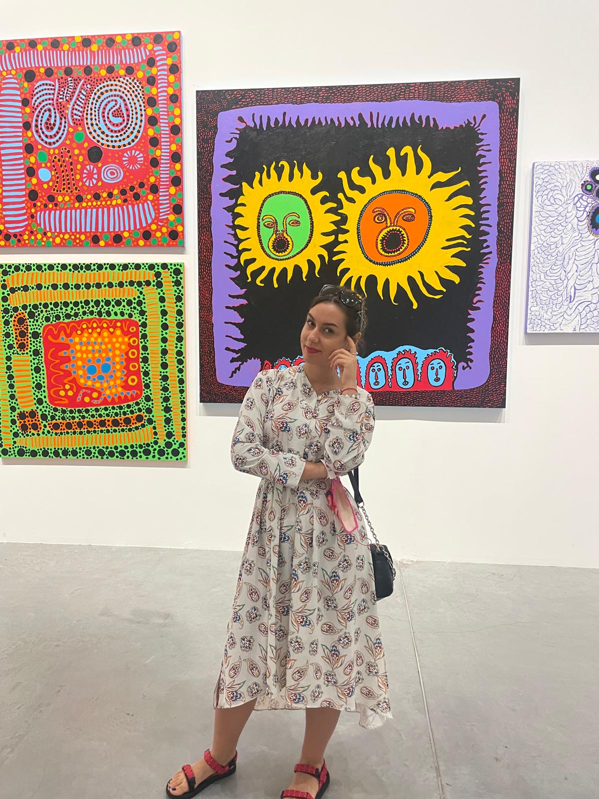 Ivaneta standing in front of a bright contemporary painting in the gallery