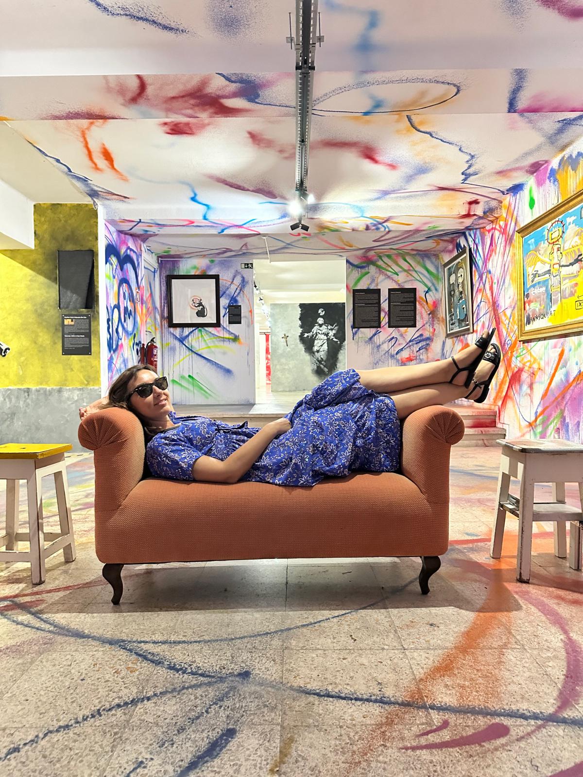 Ivaneta resting on a couch in a fully painted graffiti room