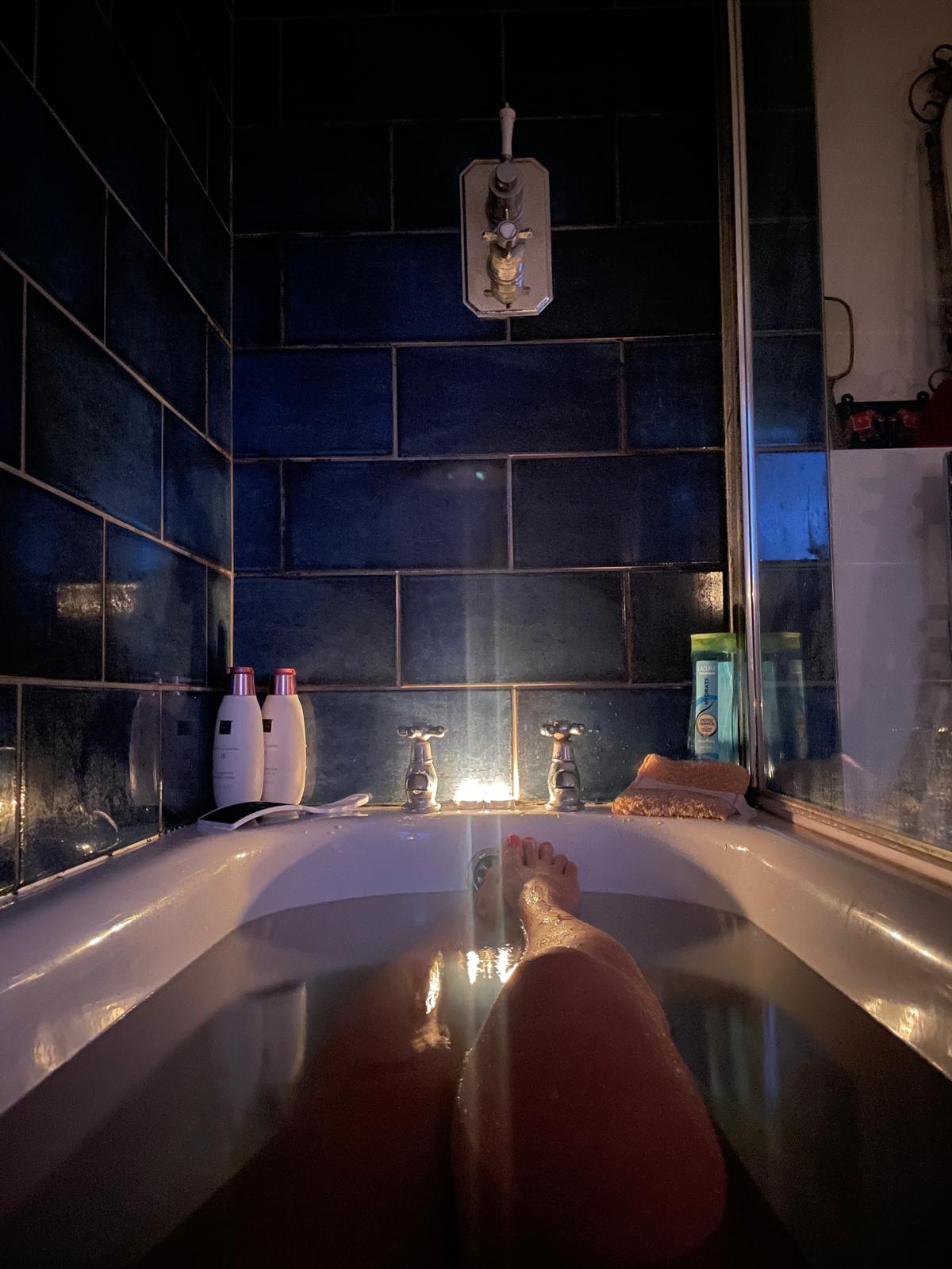 Deep blue tiled bathroom lit by a single candle