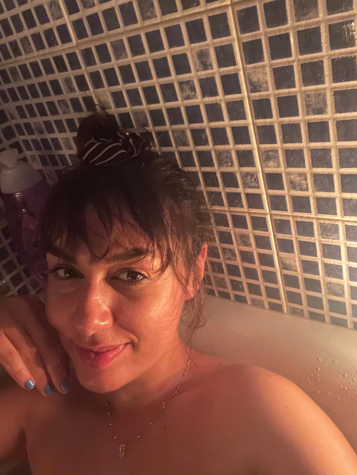 A woman resting in the bath, softened and at peace